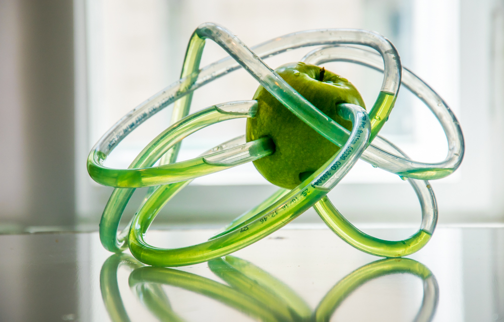 A green apple penetrated with artificial tubes circulating a green liquid